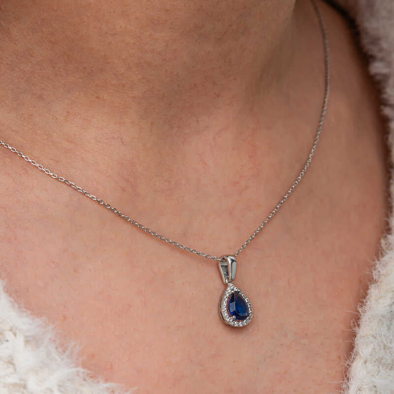 Elegant halskæde med dråbeformet blå safir i sterlingsølv med halo-design