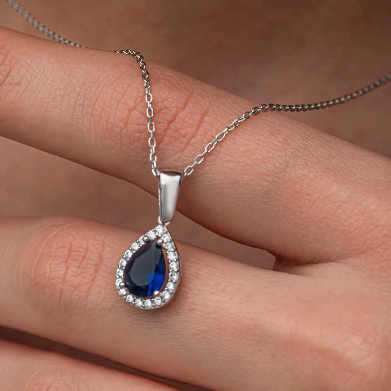 Elegant halskæde med dråbeformet blå safir i sterlingsølv med halo-design